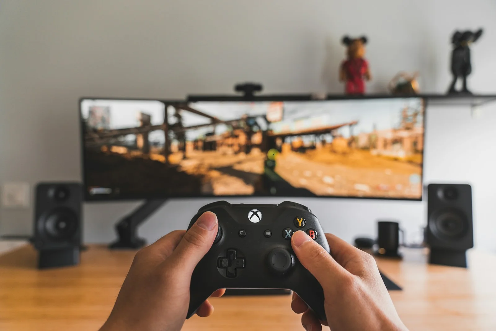 Hände an einem Xbox-Controller vor einem Monitor